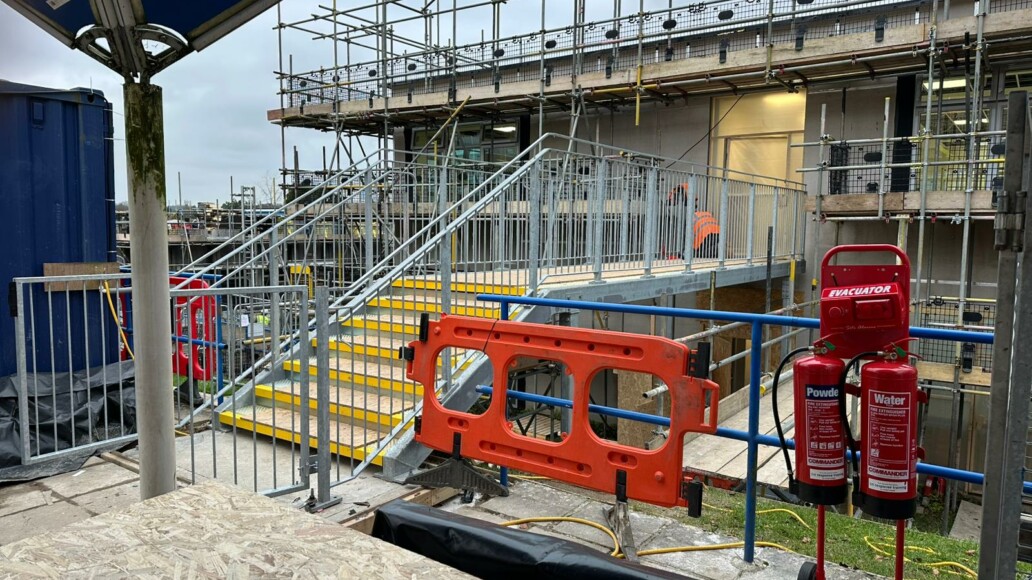 Elevated galvanized steel link bridge with access stairs and security gates