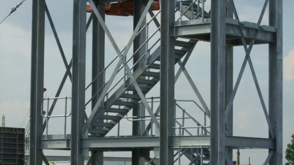 Multi-tier steel access gantry surrounding industrial process plant and pipework