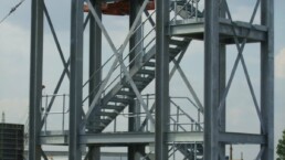 Multi-tier steel access gantry surrounding industrial process plant and pipework