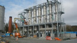 Multi-tier steel access gantry surrounding industrial process plant and pipework