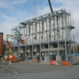Multi-tier steel access gantry surrounding industrial process plant and pipework